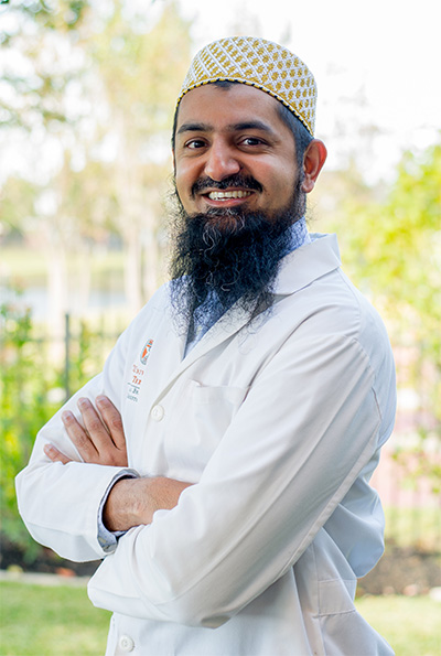 Dr. Husein Alibhai outdoors in a white coat